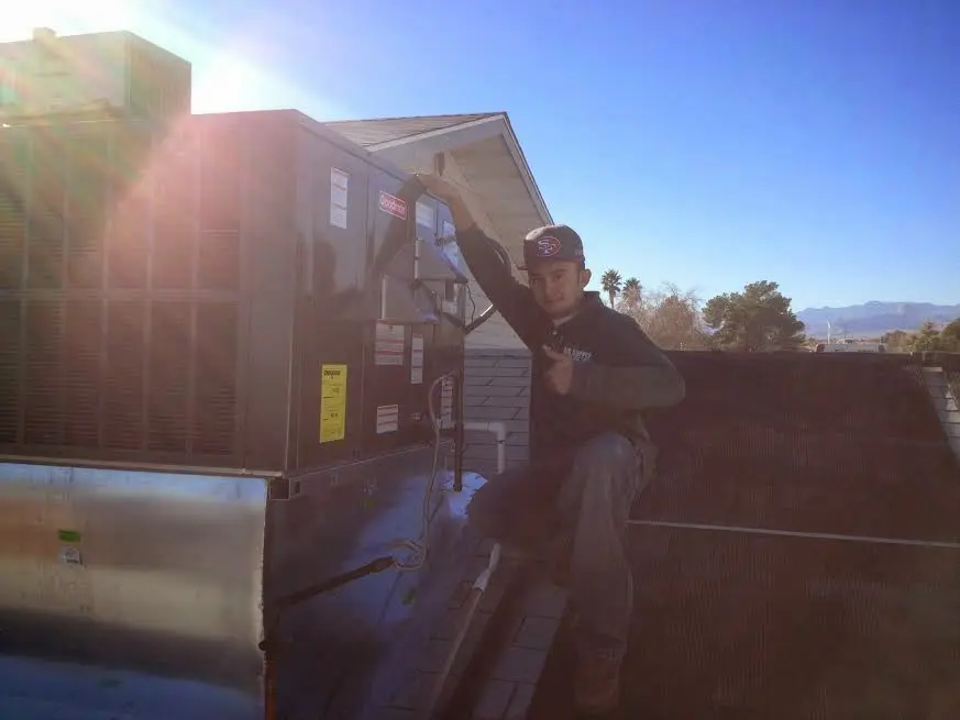 HVAC technician performing AC Tune-Up on a rooftop unit in Stockbridge